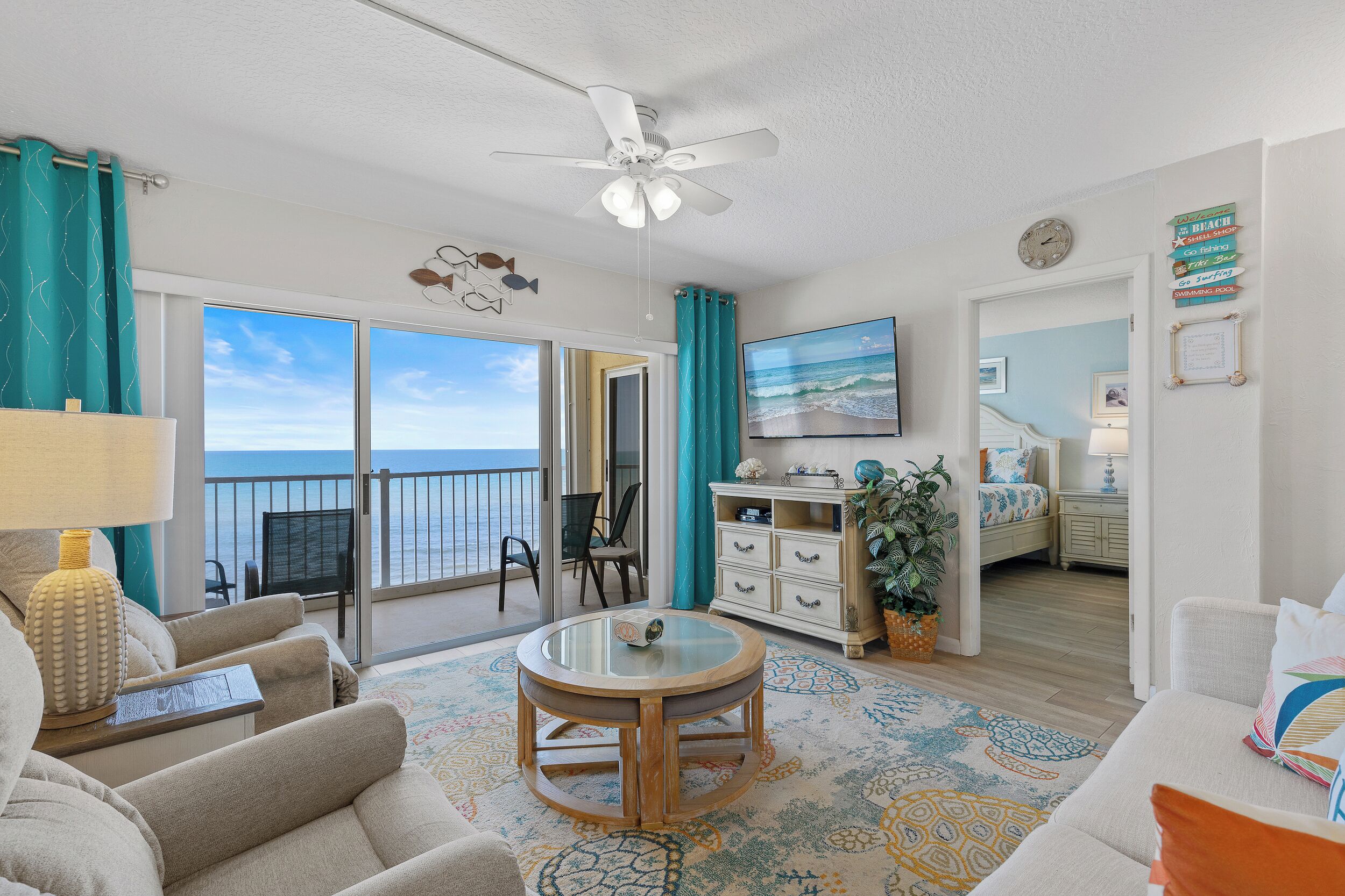 Ein geräumiger Wohnbereich mit Balkon, einem runden Holztisch und Blick auf das Meer.