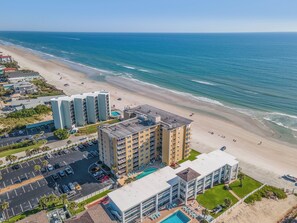 Un hôtel situé sur la côte, composé de plusieurs bâtiments, doté d’un parking et donnant accès à une plage.
