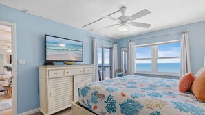 A bedroom with a bed, a ceiling fan, a television, and a view of the ocean. - Stunning Oceanfront Condo with Spectacular Views of NSB (New Smyrna Beach)