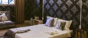 A neatly made bed with pillows and a blanket, a small bedside table with a cup, and a chair with a cushion. - Nha Saigon (Ho Chi Minh City)