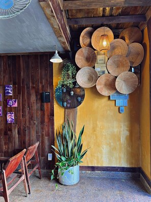 A wooden interior with a yellow wall, a ceiling fan, a hanging light fixture, and a wall-mounted power outlet. - Nha Saigon (Ho Chi Minh City)