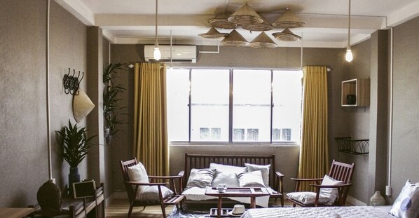 A bedroom with a bed, two chairs, a table, and a window with curtains. - Nha Saigon (Ho Chi Minh City)