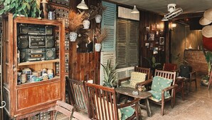 A cozy, rustic interior with wooden furniture, a vintage radio collection, and decorative plants. - Nha Saigon (Ho Chi Minh City)