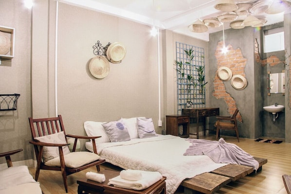 A modern bedroom with a large bed, wooden furniture, a brick wall, and a ceiling light fixture.
