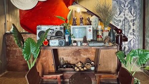 A bar area with wooden chairs, a counter with various items, and a large red wall with circular patterns. - Nha Saigon (Ho Chi Minh City)