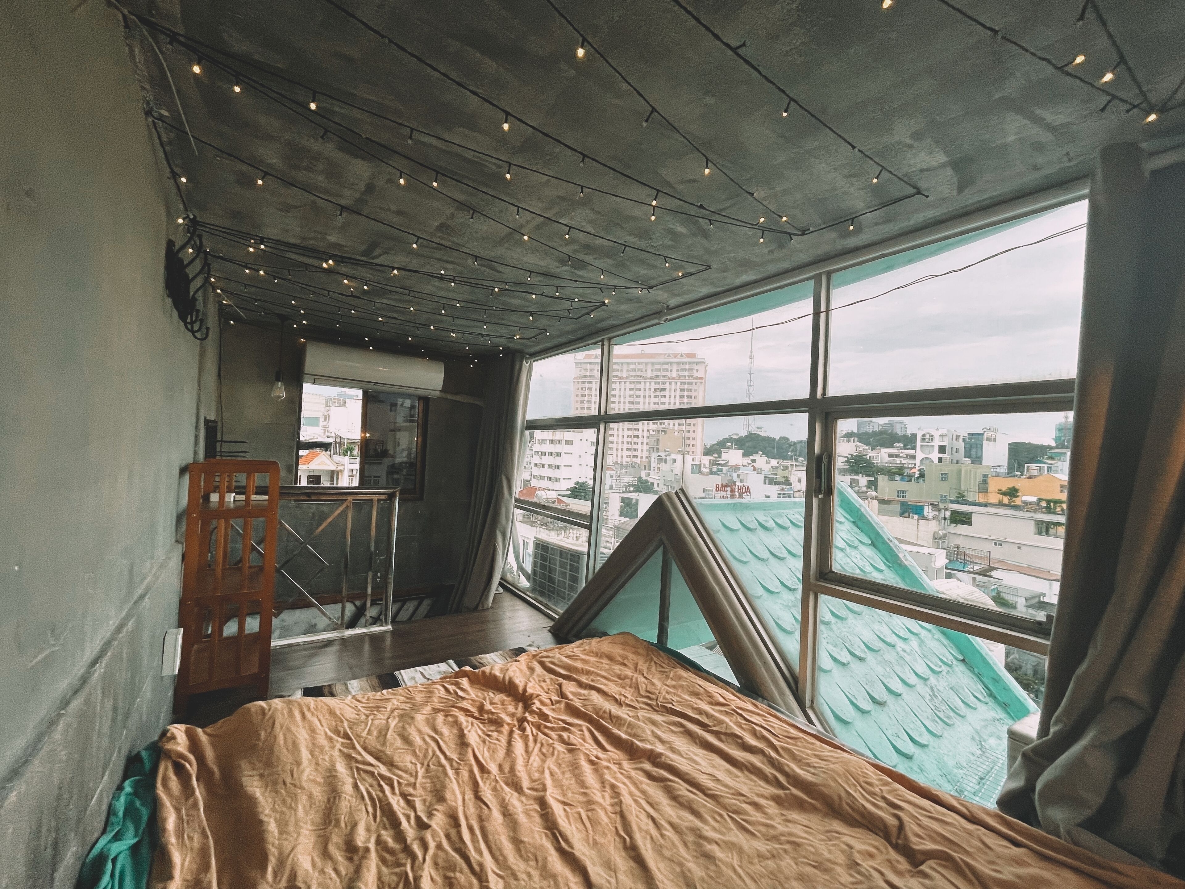 Ein Schlafzimmer mit großem Fenster, einem Bett und Blick auf die Stadt.
