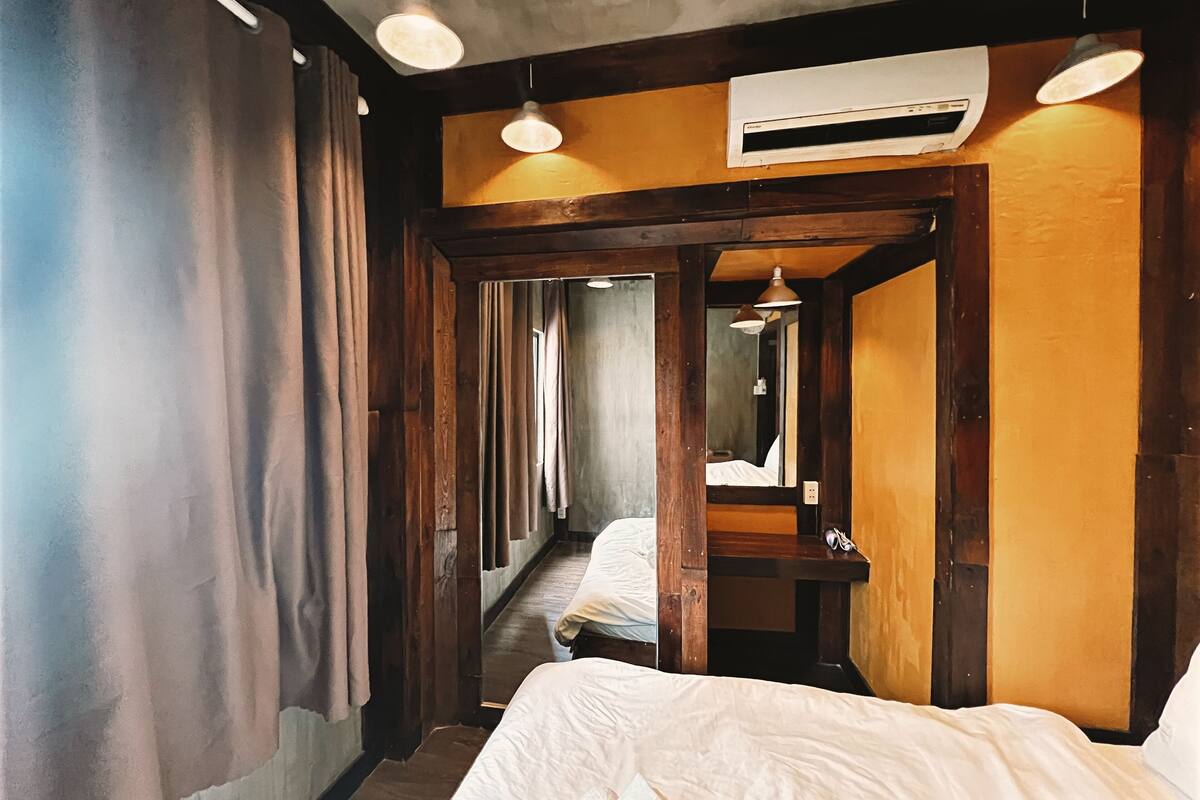 Um corredor estreito com paredes de madeira e uma cama no final.