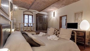 A bedroom with a large bed, a wooden dresser, a television, and a mirror.