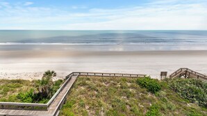 A beach view with a wooden boardwalk leading to a sandy area and a wooden staircase. - Luxury 2/2 Condo with the Best Ocean View! (New Smyrna Beach)