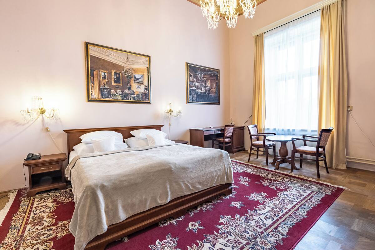 Una habitación de hotel con una cama grande, un escritorio y una mesa de comedor con sillas.
