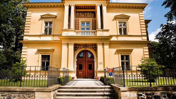 A stately building with a grand entrance, a symmetrical facade, and a central door flanked by columns. - Vila Lanna (Prague)