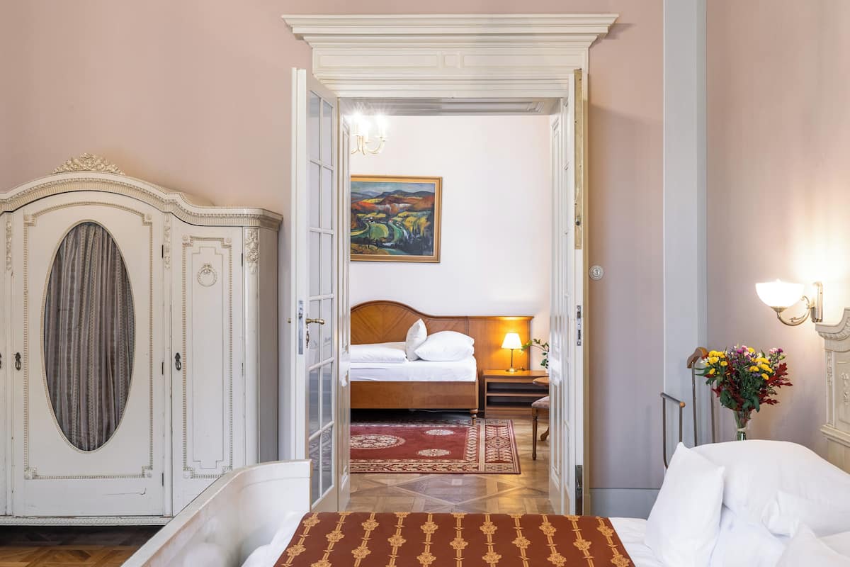 Habitación de hotel con cama, mesita de noche, lámpara, un cuadro en la pared y armario.