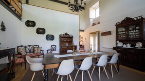 Un comedor con una mesa larga, seis sillas, una araña y un aparador de madera con puertas de cristal.