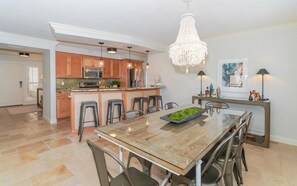 A modern kitchen with wooden cabinets, stainless steel appliances, and a central island with bar stools. - Buttonwood 442 (Sarasota)