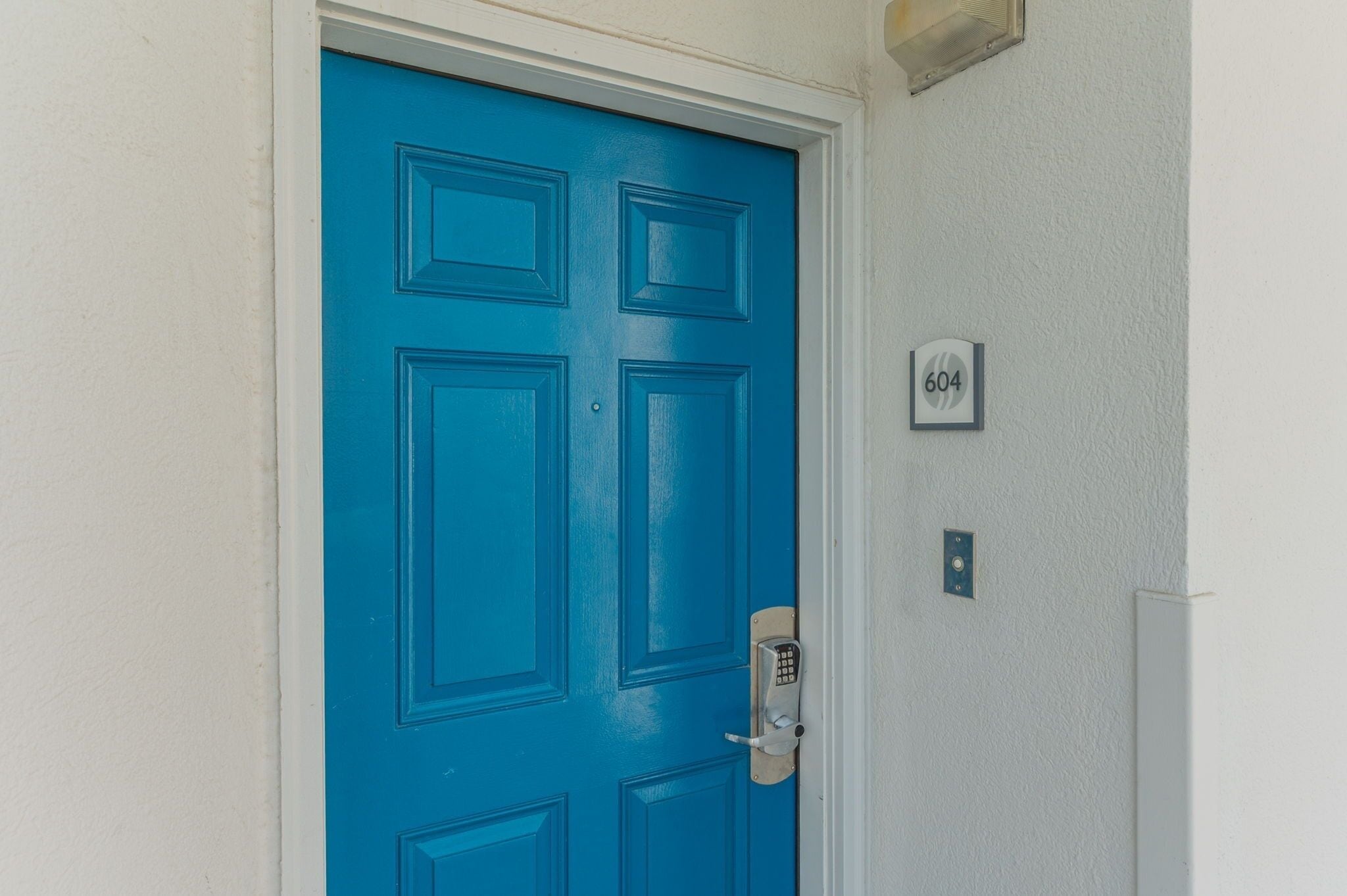 A blue door with a keypad lock and a number plate indicating room 604.
