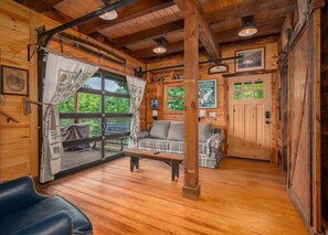 Interior de uma cabana de madeira com um sofá, um banco e uma mesa de jantar.