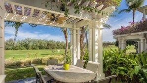Un porche cubierto con una mesa y sillas, con vista a un campo de golf.