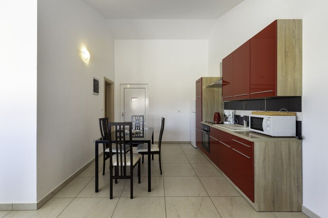 A compact kitchen with a dining area, featuring a microwave, stove, and cabinets.