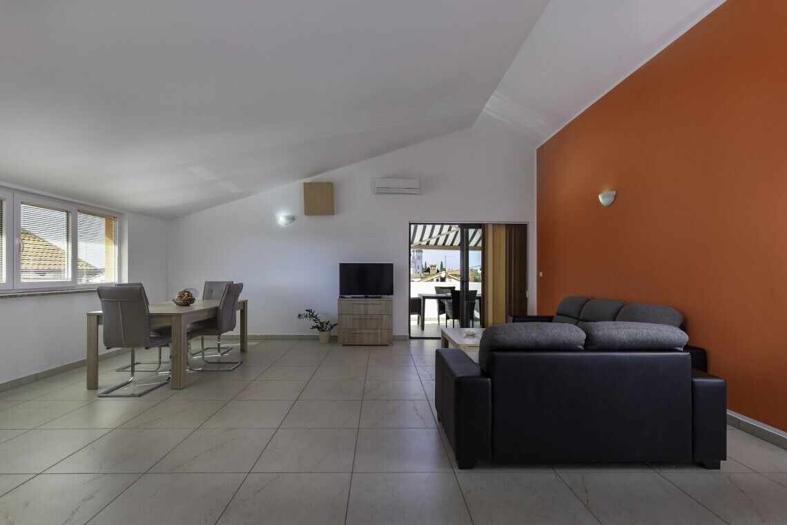 A spacious living area with a dining table, sofa, and TV.