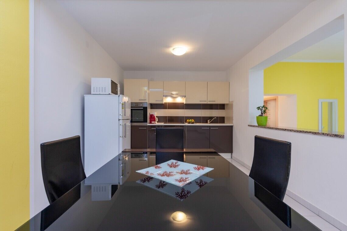 A modern kitchen with a dining area, featuring a refrigerator, microwave, and stove.