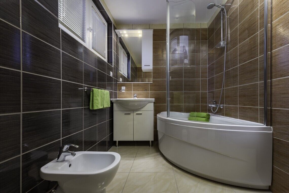 A modern bathroom with a bidet, sink, and a walk-in shower.