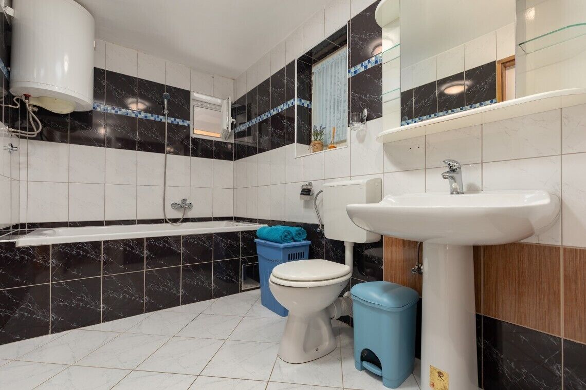 A bathroom with a bathtub, toilet, sink, and a mirror.