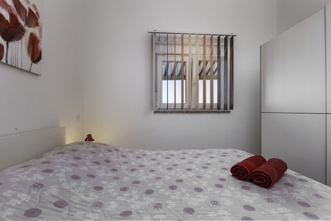 Una camera da letto con un letto, una finestra con persiane e un armadio.