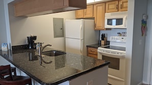A kitchen with granite countertops, a stainless steel sink, a double-door refrigerator, a microwave, and a stove. - Welcome to Paradise! (Jensen Beach)