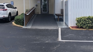 The entrance to Island Beach Resort with a covered walkway, a parking area, and a white fence. - Welcome to Paradise! (Jensen Beach)