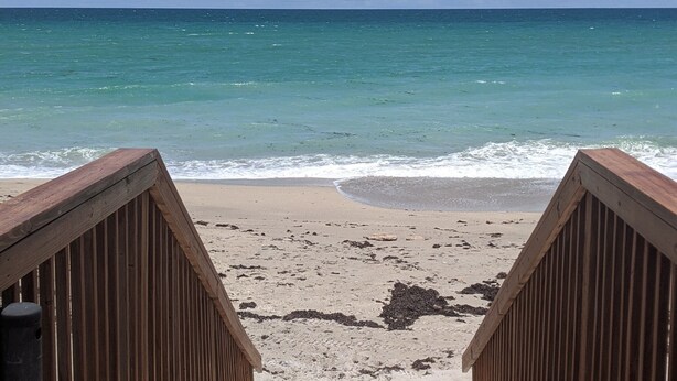 A wooden boardwalk leading to a beach with clear blue water and a partly cloudy sky. - Welcome to Paradise! (Jensen Beach)