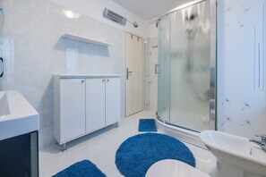 A modern bathroom with a white sink, a glass shower enclosure, and a white cabinet. - Fiorela (Rovinj)