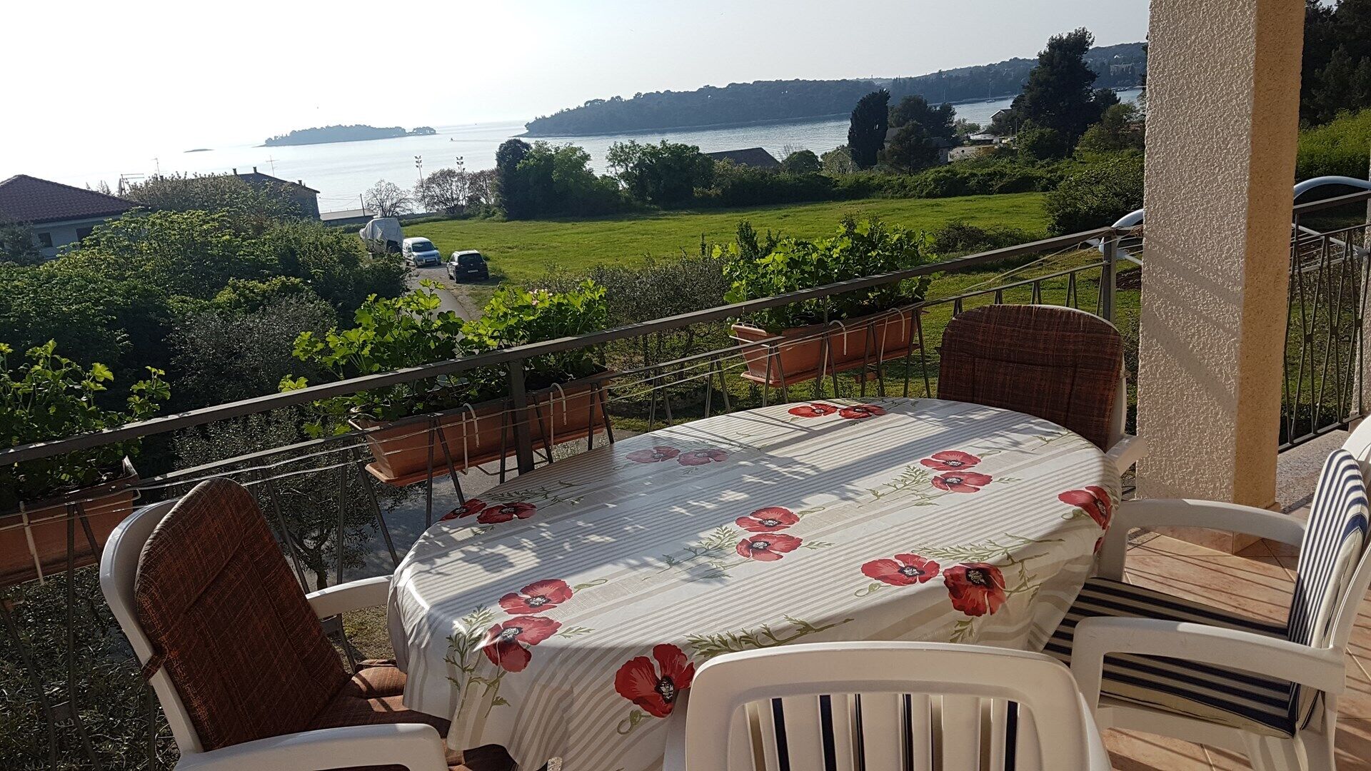 Una terraza con mesa y sillas, con vista a un cuerpo de agua y follaje.
