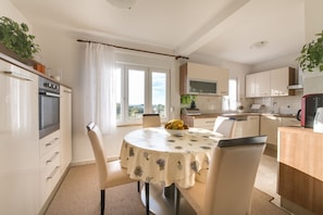 Enjoy meals in the spacious kitchen and dining area with a central island, dining table, and large window offering a view of the outdoors.