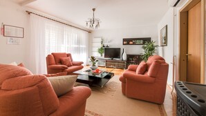Ein Wohnzimmer mit zwei orangen Sesseln, einem Couchtisch, einem Fernseher und einem Kamin.