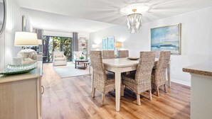 Un comedor con sillas de mimbre, una mesa blanca y un candelabro.