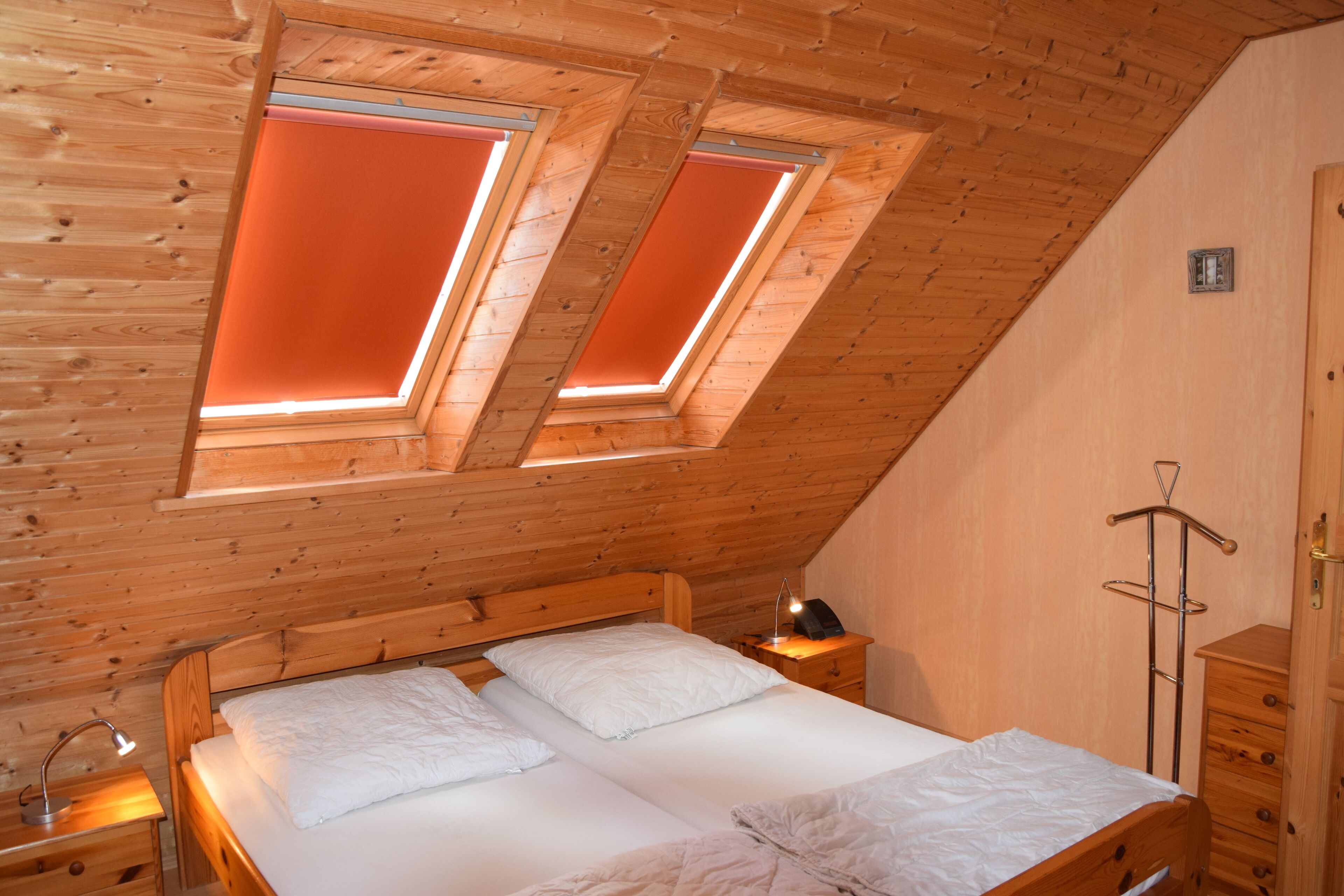A bedroom with a sloped ceiling, two skylights, a wooden bed, a bedside table, and a wardrobe. - Vacation home starboard quietly located large terrace only 300m to the beach / sea (Friedrichskoog-Spitze)