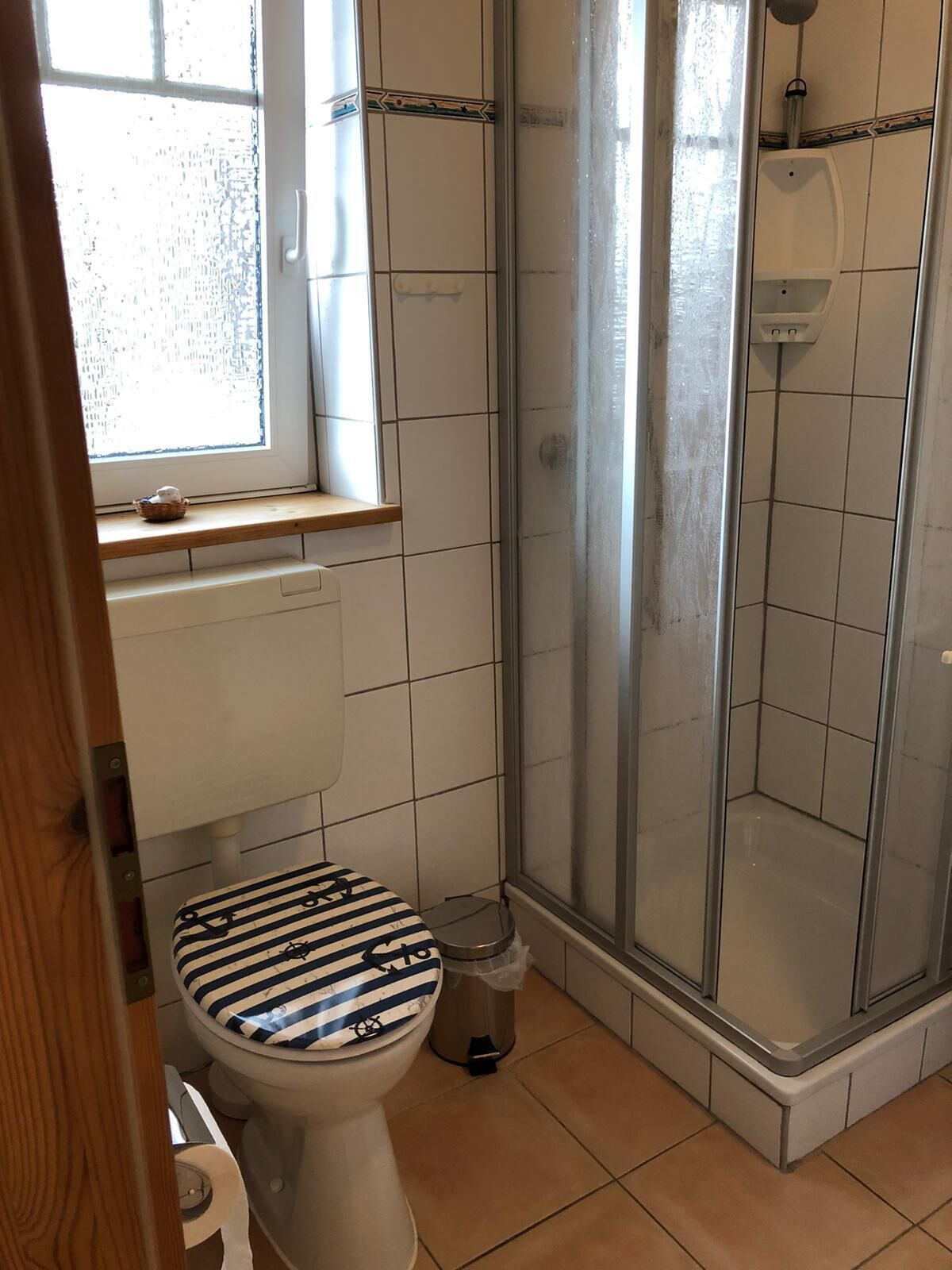 Un baño con inodoro, cabina de ducha y ventana.