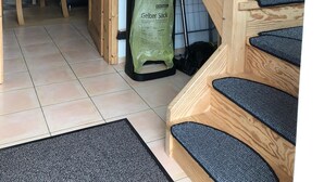 A staircase with wooden railings and carpeted steps, leading to a room with a chair and a trash bin labeled 'Gelber Sack'. - Vacation home starboard quietly located large terrace only 300m to the beach / sea (Friedrichskoog-Spitze)