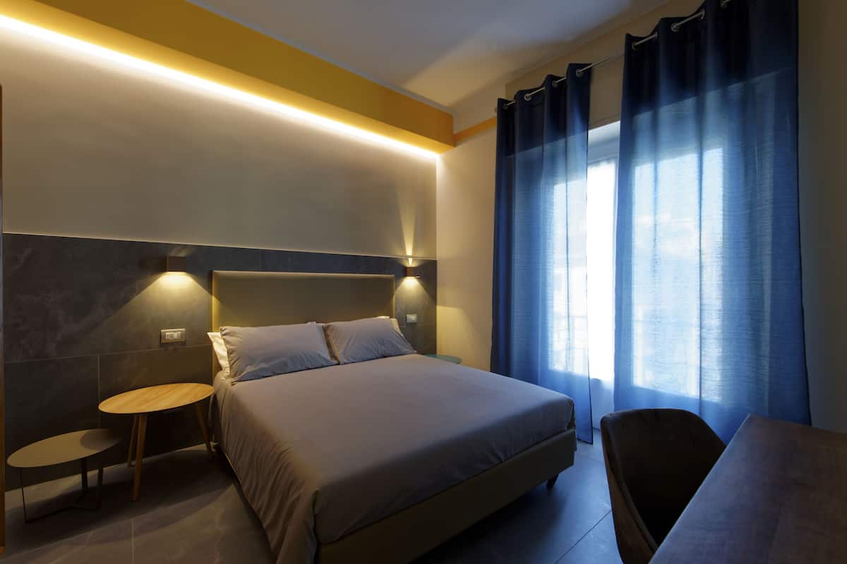 A modern hotel room with a large bed, a small round table, and a chair.