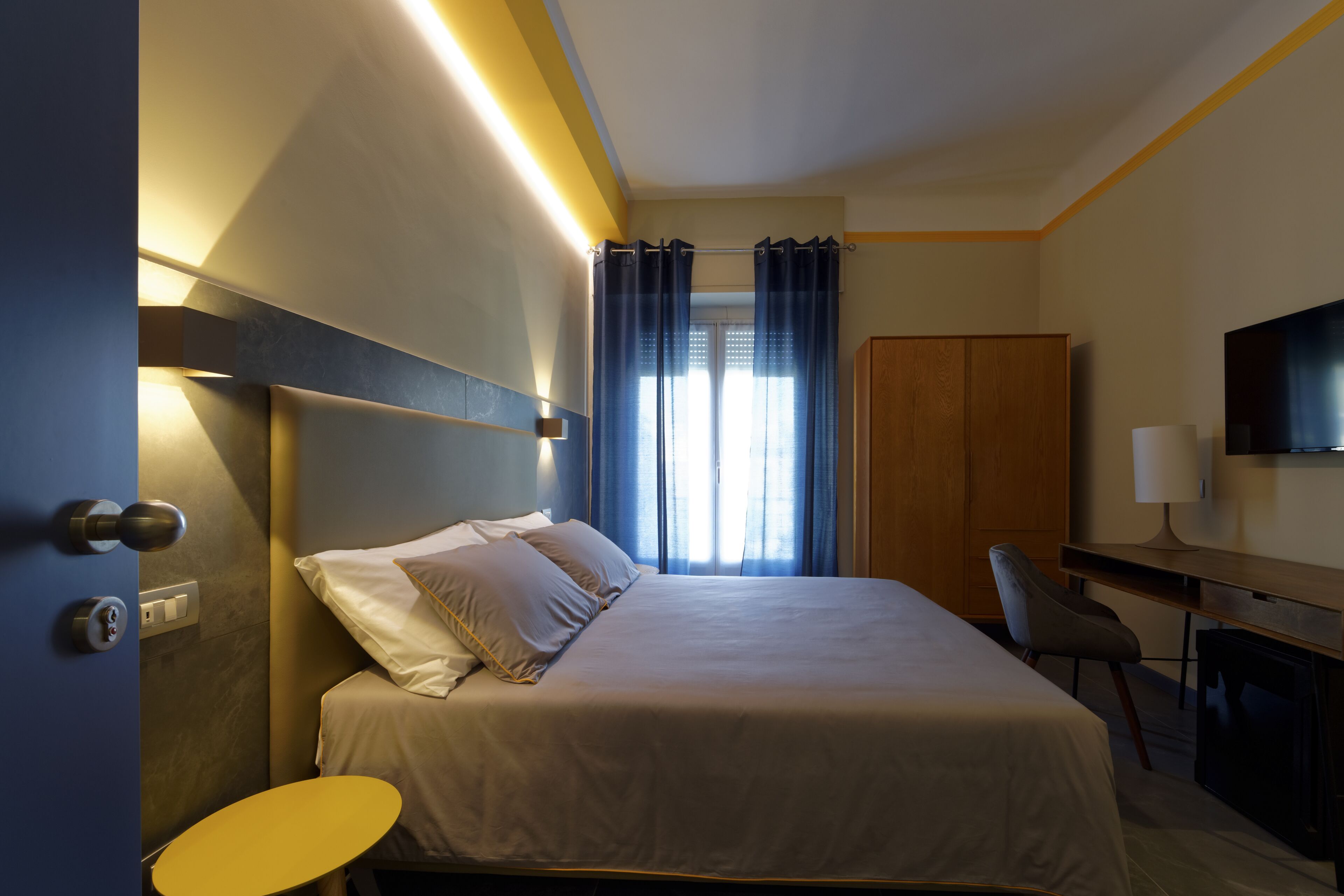 Een hotelkamer met een bed, een bureau, een stoel, een televisie en een kledingkast.