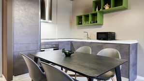 Una cocina moderna con microondas integrado, campana extractora de acero inoxidable y un mueble verde sobre la encimera.