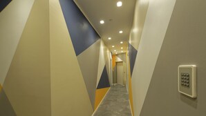 Un pasillo con patrones geométricos en la pared y un teclado de seguridad a la derecha.
