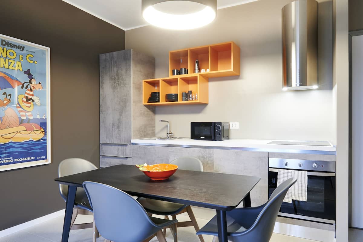 A modern kitchen with a dining table, chairs, a microwave, and a built-in oven.