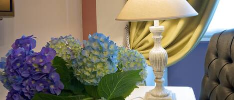 Una mesa blanca con un florero de hortensias y una lámpara blanca.