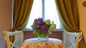 Uma mesa com toalha florida, um vaso de flores e duas cadeiras.