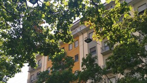 Um edifício com várias andares, varandas e uma árvore em primeiro plano.