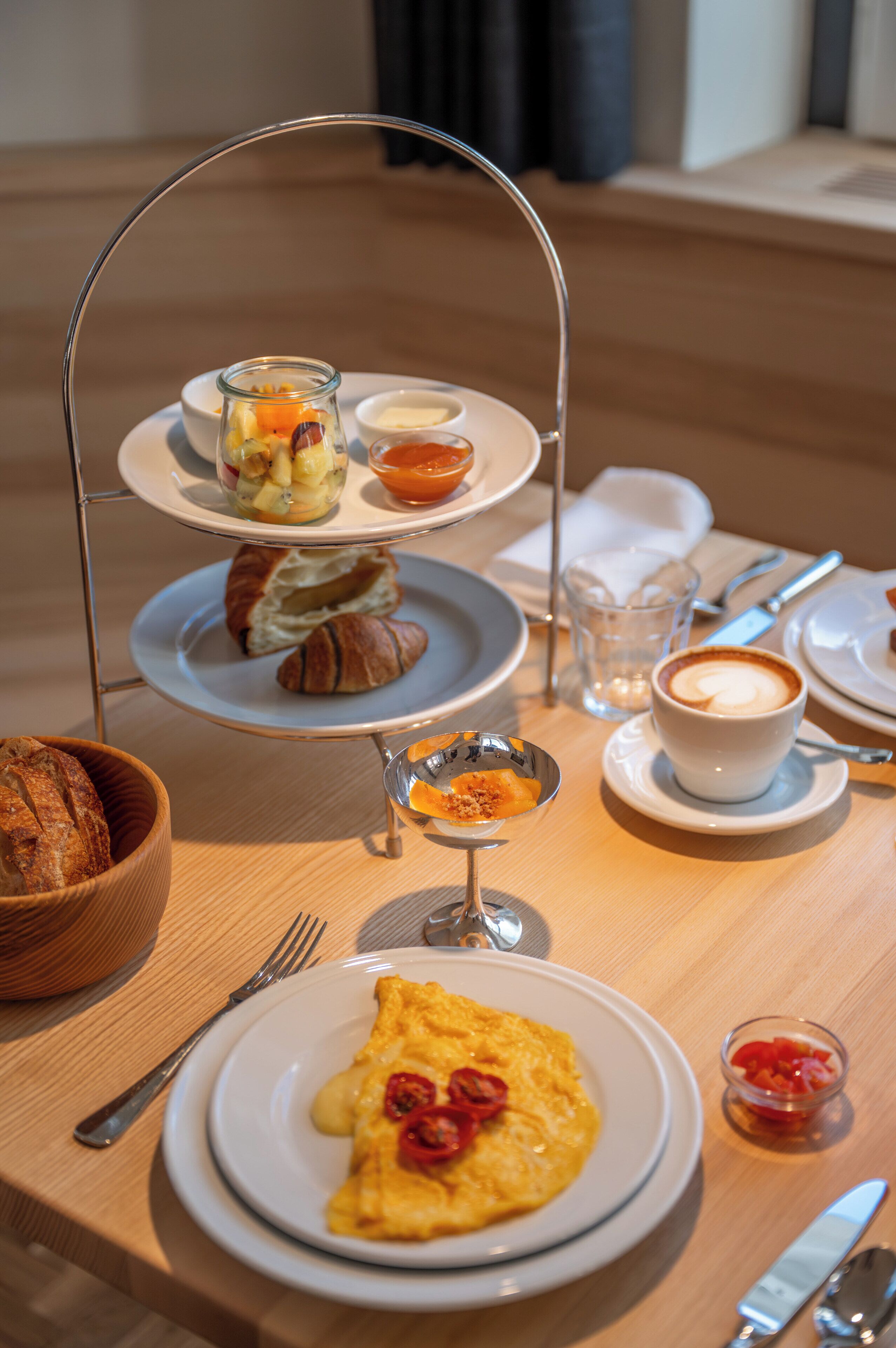 A breakfast setup with croissants, fruit, and coffee on a tray.