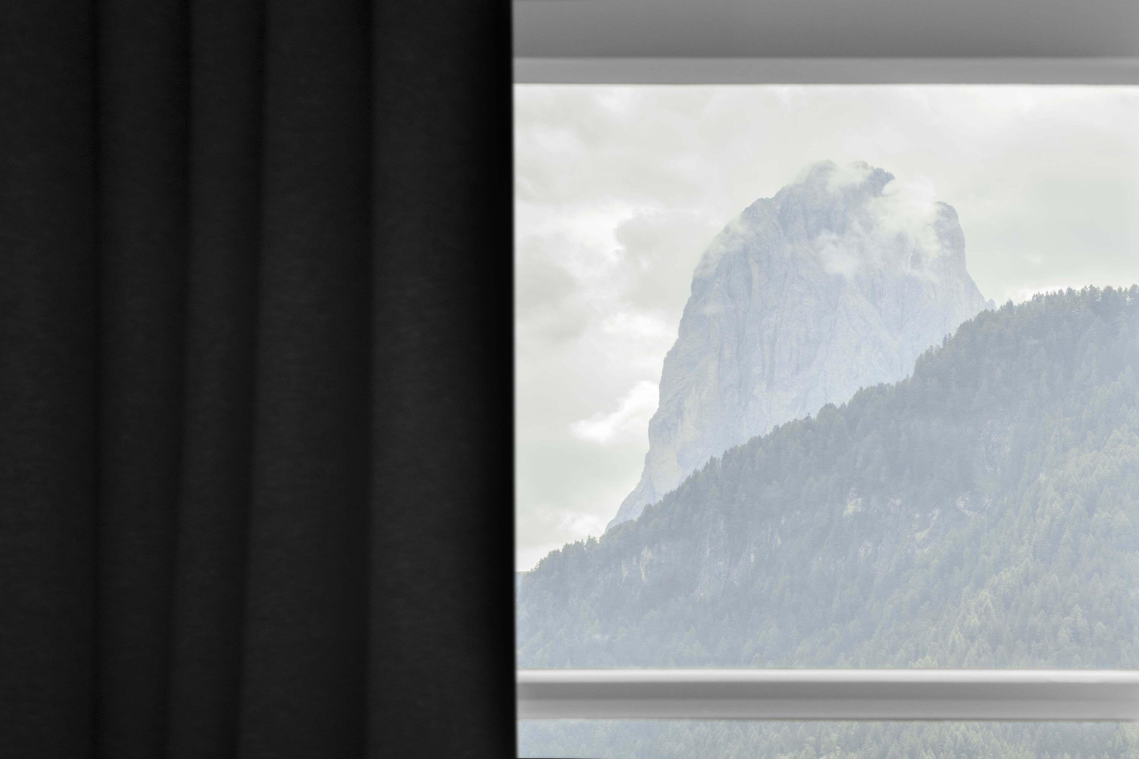 Une fenêtre donnant sur une montagne et une forêt.