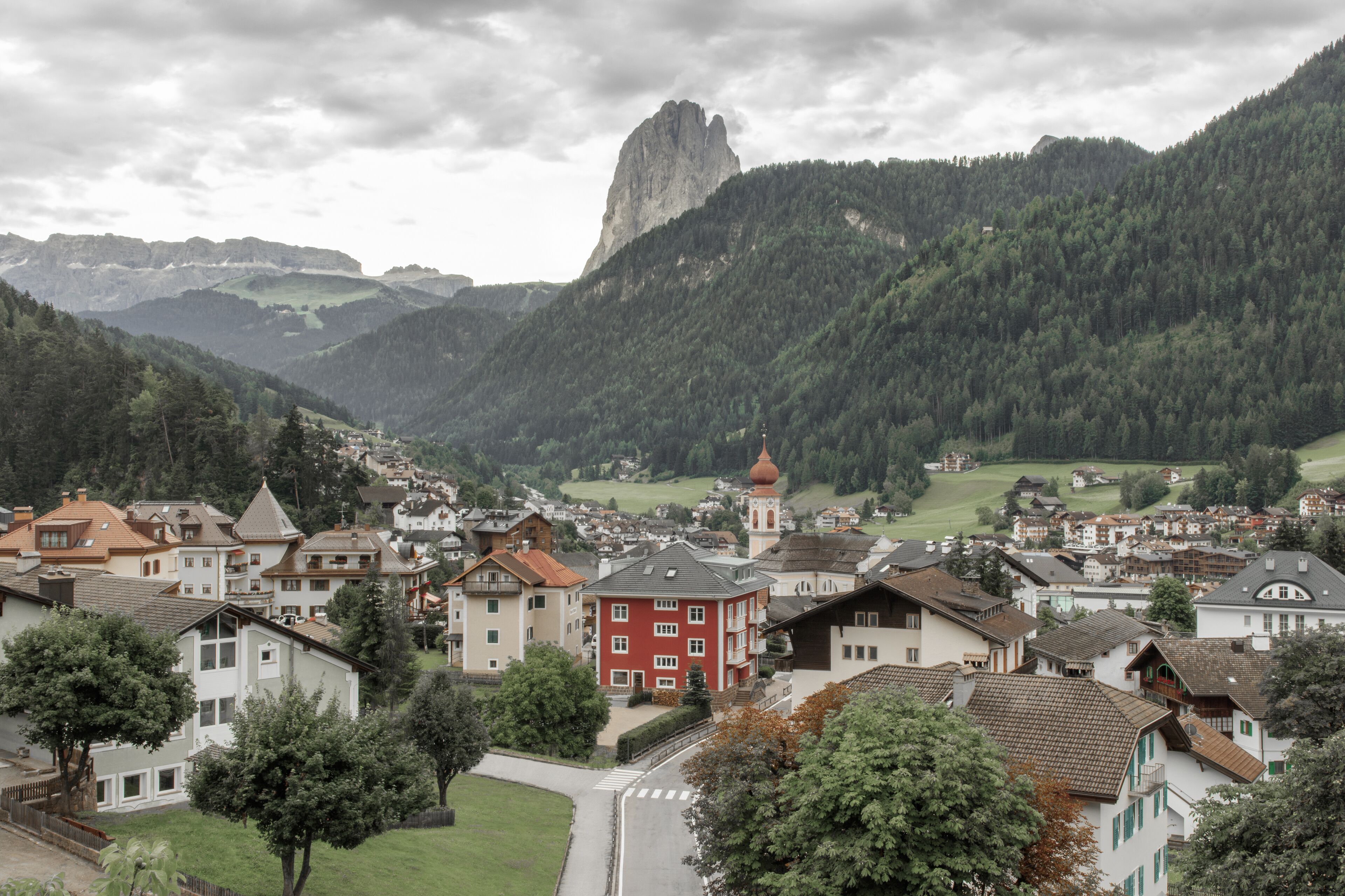A town with a prominent church tower, surrounded by residential buildings and a mountain backdrop.