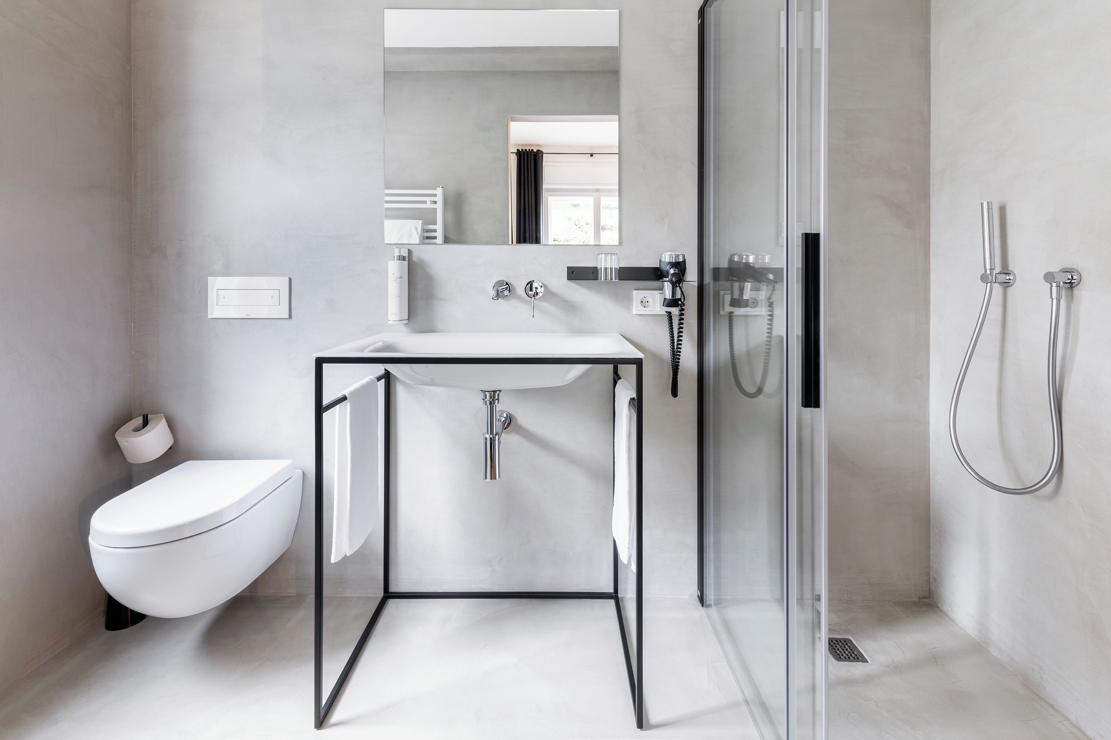 A modern bathroom with a glass-enclosed shower, a white toilet, and a minimalist sink.